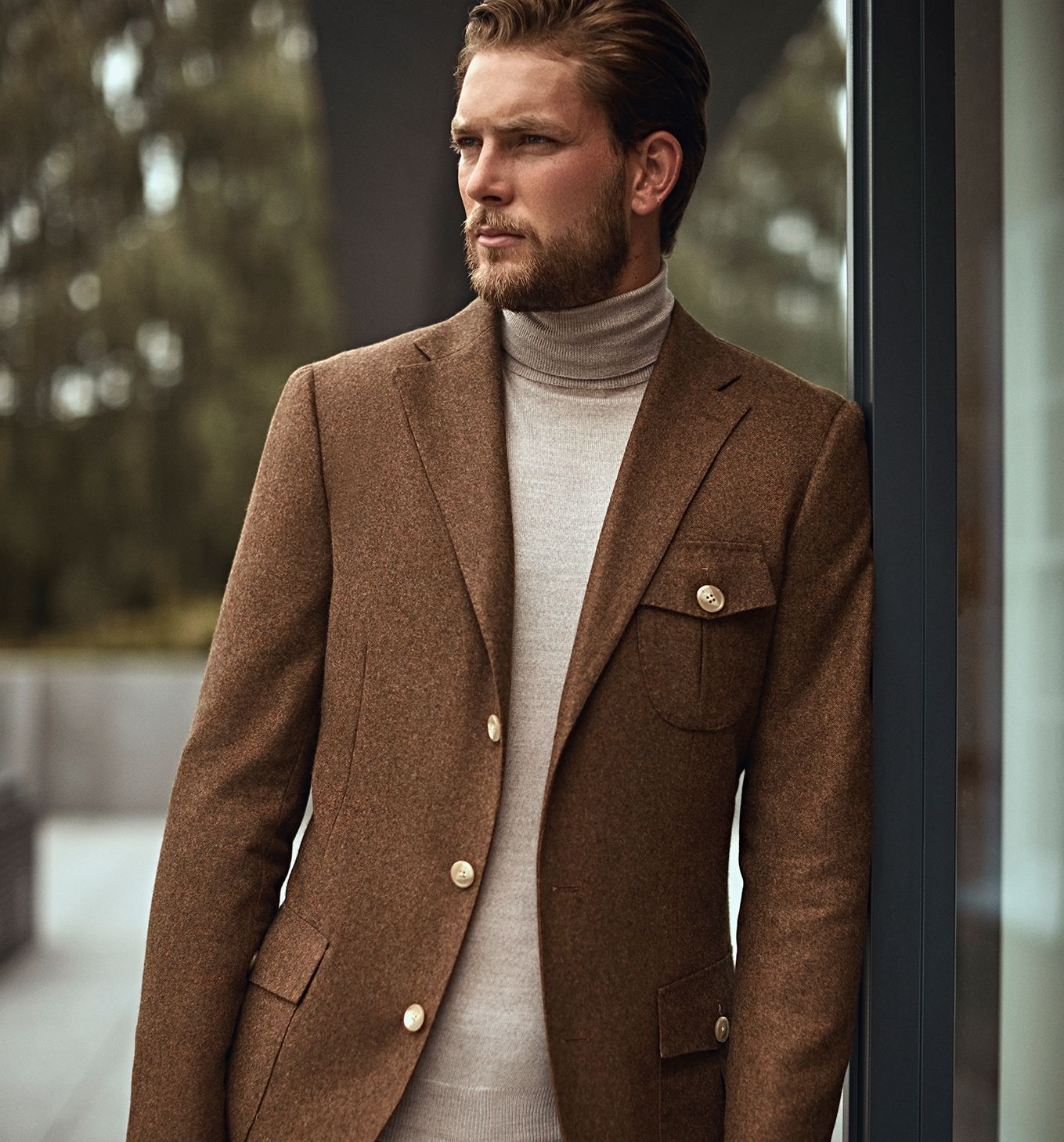 Model looking dapper in custom made brown structured jacket, layered over a cream turtleneck sweater